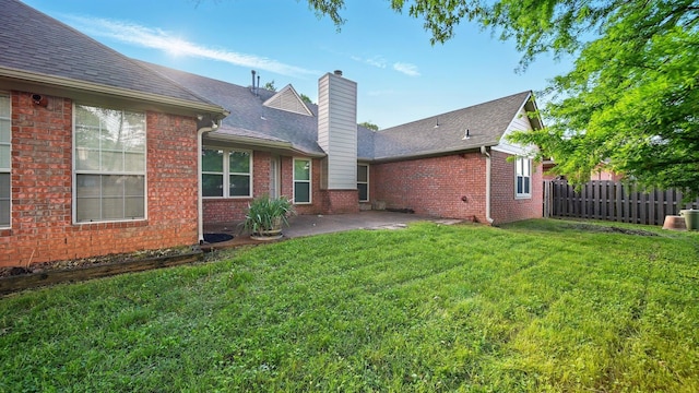 rear view of property with a chimney, a patio, brick siding, and roof with shingles