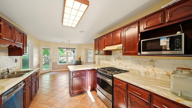 kitchen featuring appliances with stainless steel finishes, under cabinet range hood, a sink, a peninsula, and light countertops
