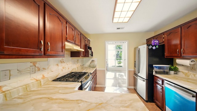 kitchen featuring stainless steel appliances, under cabinet range hood, tasteful backsplash, and light tile patterned floors