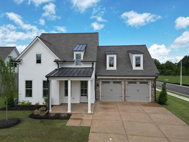 view of front of house featuring roof with shingles, concrete driveway, a standing seam roof, a front lawn, and covered porch