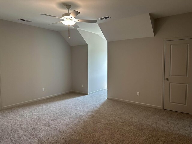 carpeted empty room with a ceiling fan, baseboards, and lofted ceiling