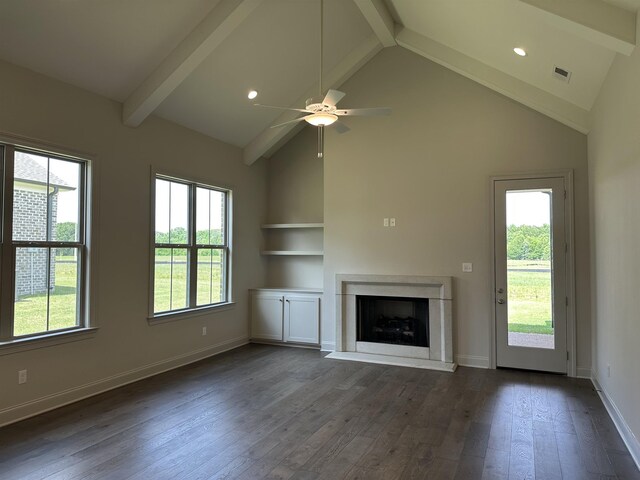 unfurnished living room featuring healthy amount of natural light, a premium fireplace, dark wood-type flooring, beamed ceiling, and high vaulted ceiling