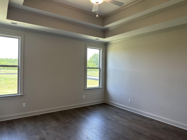 spare room with a raised ceiling, ornamental molding, dark wood-style flooring, and baseboards