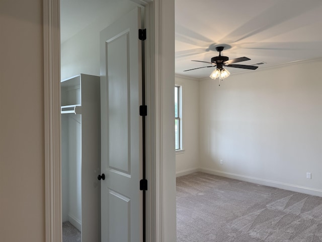 unfurnished room with light carpet, a ceiling fan, baseboards, and ornamental molding