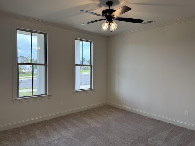 carpeted spare room with ornamental molding, baseboards, and a ceiling fan