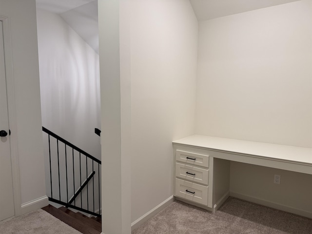 unfurnished office featuring light carpet, built in study area, and baseboards