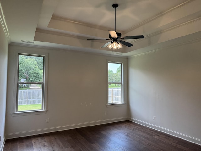 unfurnished room featuring a raised ceiling, ornamental molding, dark wood-style floors, baseboards, and a ceiling fan