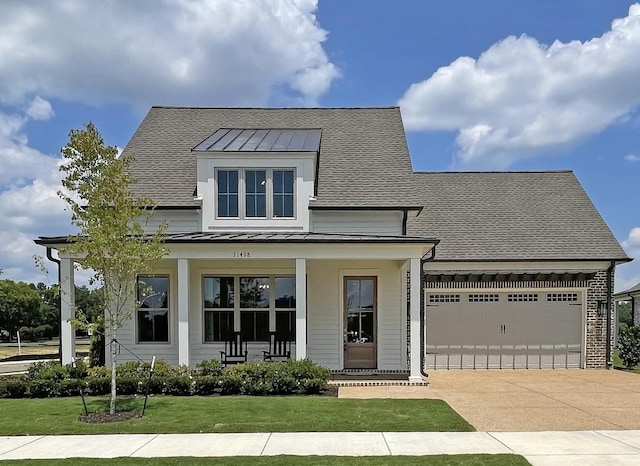 modern farmhouse style home featuring a standing seam roof, a porch, an attached garage, metal roof, and a front lawn