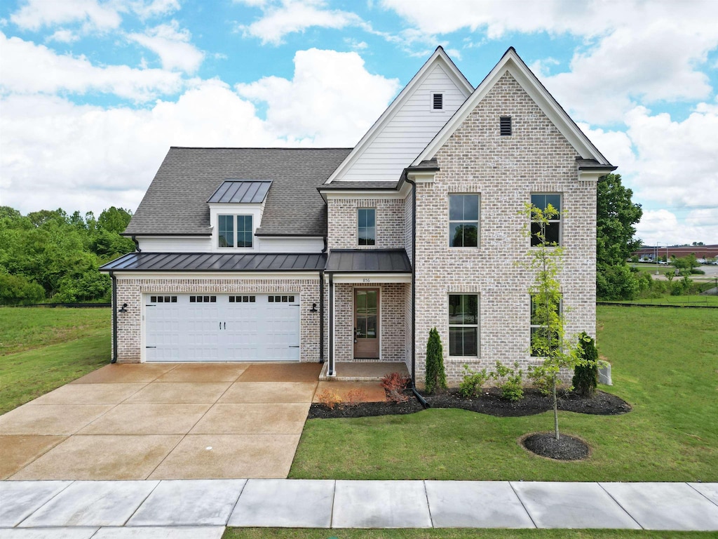 view of front of property with brick siding, a front lawn, a standing seam roof, and driveway