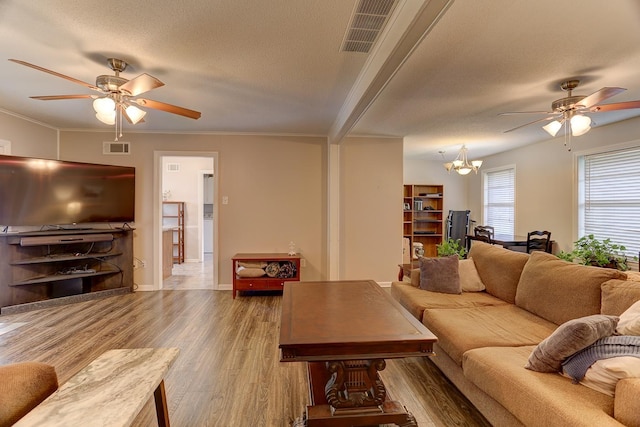 living area with a ceiling fan, wood finished floors, a chandelier, a textured ceiling, and baseboards