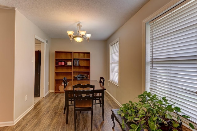 dining area featuring a chandelier, wood finished floors, a textured ceiling, and baseboards