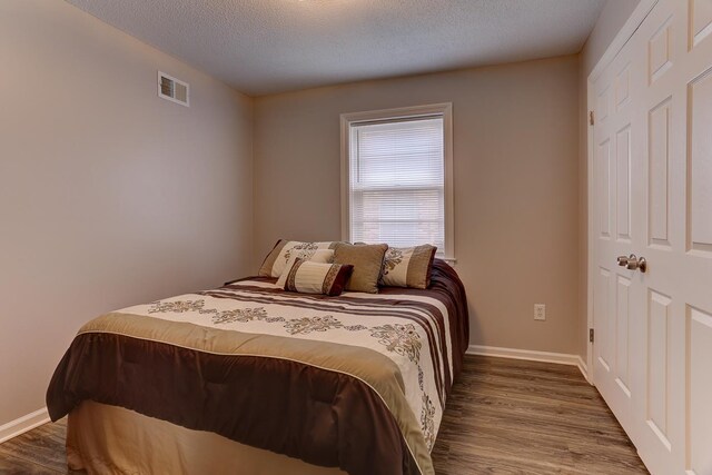 bedroom featuring wood finished floors, baseboards, and a textured ceiling