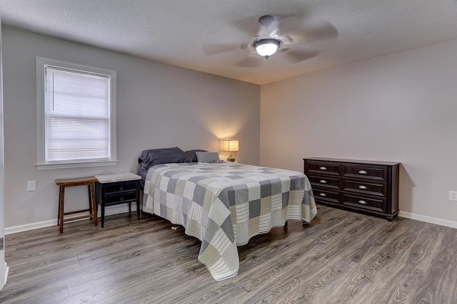 bedroom with wood finished floors, baseboards, a ceiling fan, and a textured ceiling
