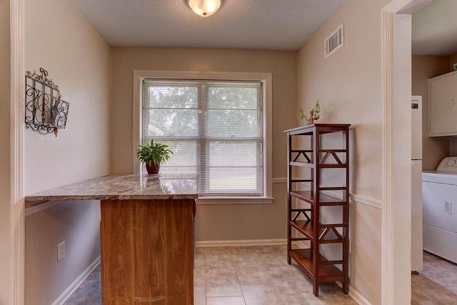 kitchen with washer / dryer, plenty of natural light, baseboards, and light stone counters