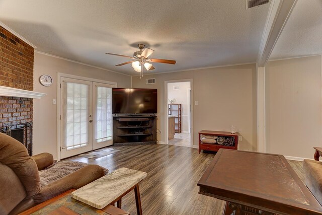 living room featuring ceiling fan, a fireplace, wood finished floors, crown molding, and french doors