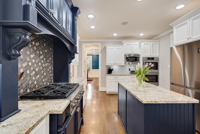 kitchen featuring appliances with stainless steel finishes, ornamental molding, backsplash, white cabinets, and wood finished floors