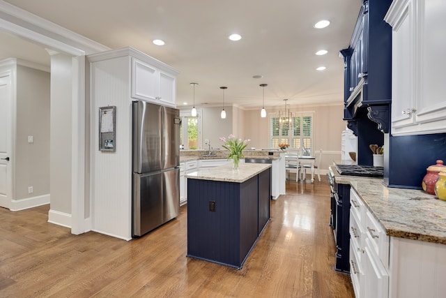 kitchen featuring appliances with stainless steel finishes, a peninsula, wood finished floors, ornamental molding, and white cabinets