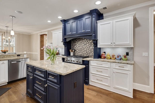 kitchen featuring stainless steel appliances, white cabinetry, crown molding, decorative backsplash, and wood finished floors