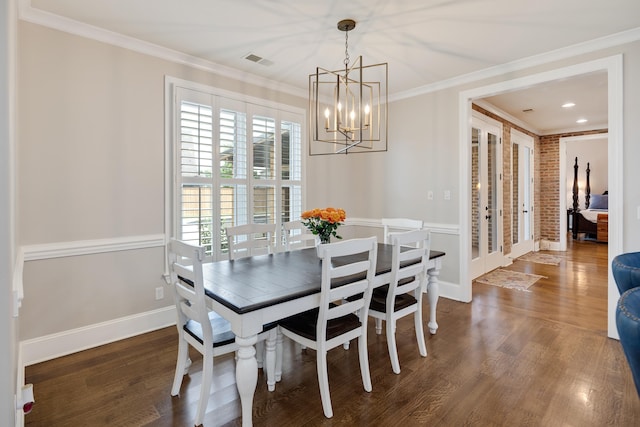 dining space featuring a chandelier, ornamental molding, wood finished floors, and baseboards