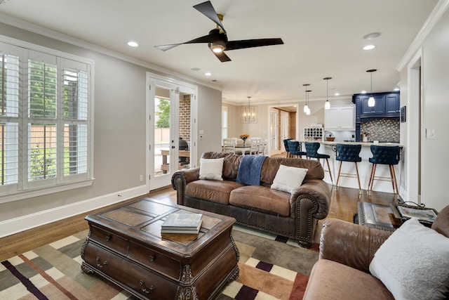 living area featuring crown molding, a chandelier, recessed lighting, ceiling fan, and baseboards