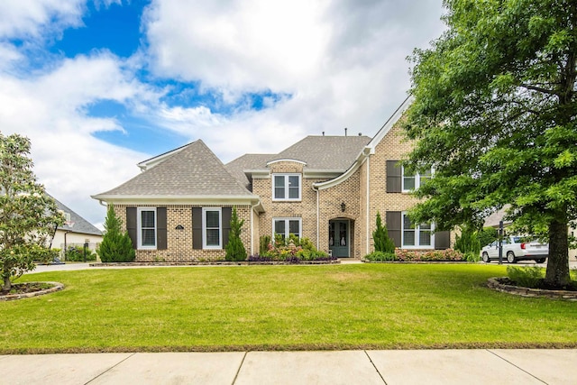 view of front of property featuring brick siding, a front lawn, and a shingled roof
