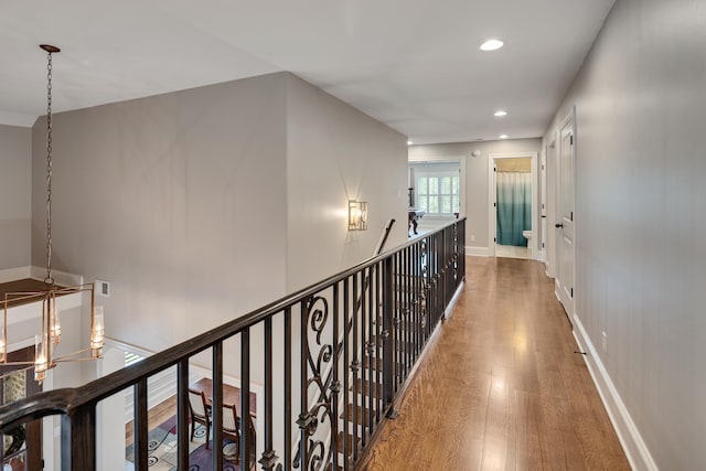 hallway with wood finished floors, recessed lighting, an upstairs landing, and baseboards