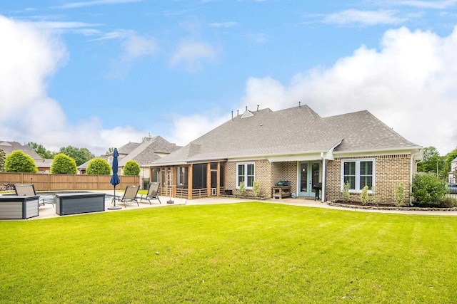 back of house with a sunroom, a covered hot tub, a patio, brick siding, and roof with shingles