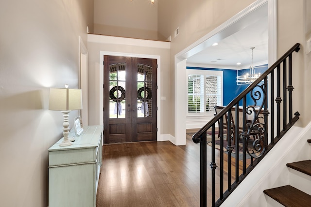 foyer with a chandelier, dark wood-type flooring, french doors, and stairway