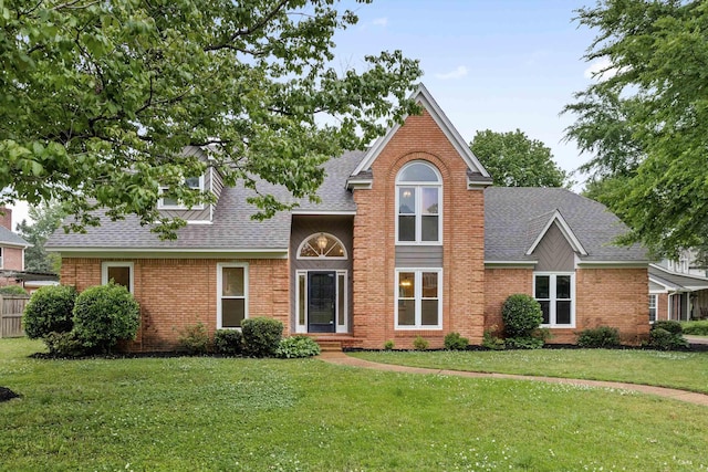 traditional-style home featuring a shingled roof, brick siding, and a front yard