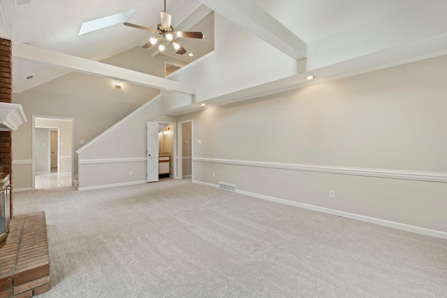 unfurnished living room featuring ceiling fan, baseboards, carpet, a skylight, and high vaulted ceiling