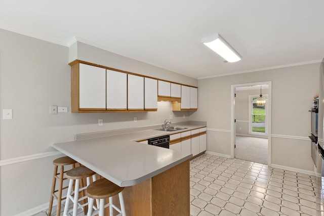 kitchen featuring light countertops, white cabinetry, a breakfast bar, baseboards, and ornamental molding