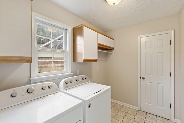 clothes washing area with cabinet space, independent washer and dryer, baseboards, and a textured ceiling