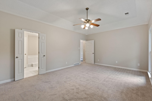 unfurnished bedroom featuring ornamental molding, light carpet, baseboards, connected bathroom, and a raised ceiling
