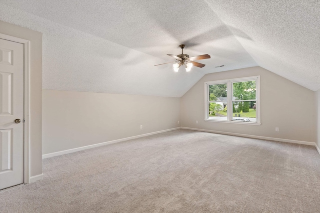 bonus room with a textured ceiling, a ceiling fan, baseboards, lofted ceiling, and carpet