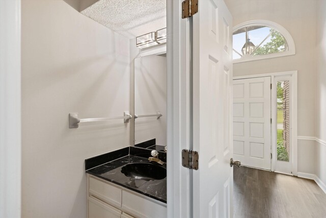 bathroom featuring wood finished floors, vanity, baseboards, and a textured ceiling
