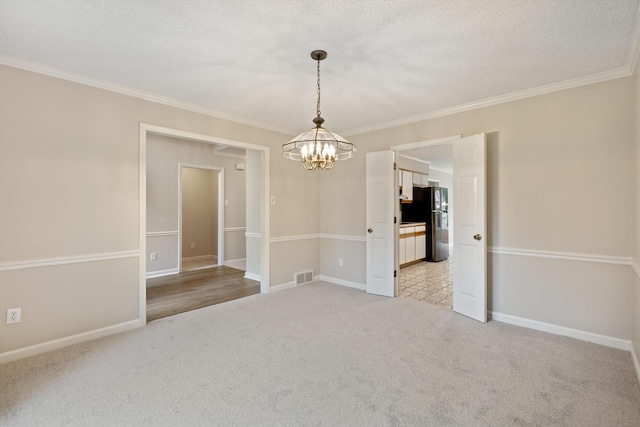 spare room with a chandelier, light carpet, crown molding, baseboards, and a textured ceiling