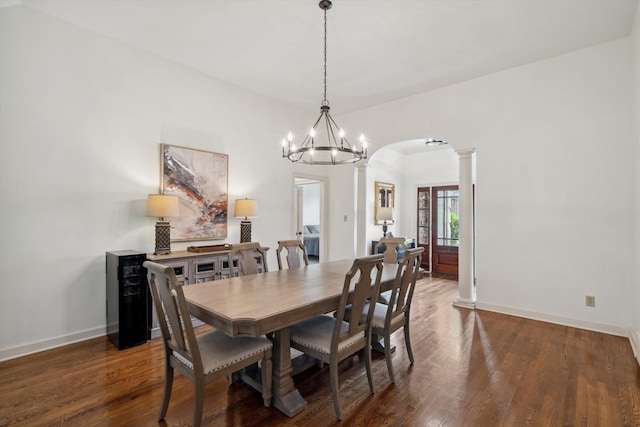 dining room with arched walkways, baseboards, a chandelier, wood finished floors, and ornate columns