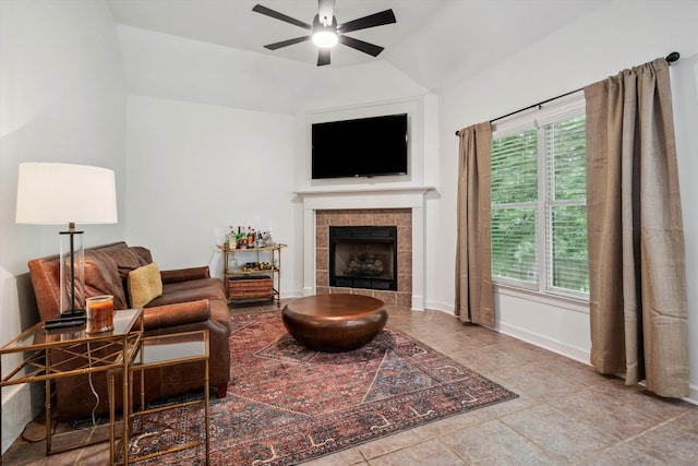 living room with ceiling fan, a tile fireplace, vaulted ceiling, baseboards, and tile patterned flooring