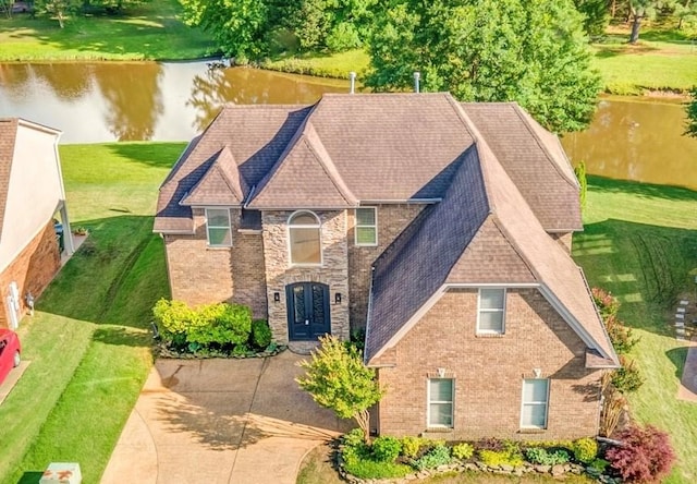 view of front of property with a water view, brick siding, a front yard, french doors, and roof with shingles
