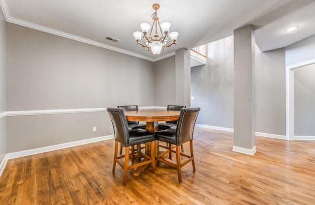 dining room featuring baseboards, crown molding, a chandelier, and light wood-style flooring