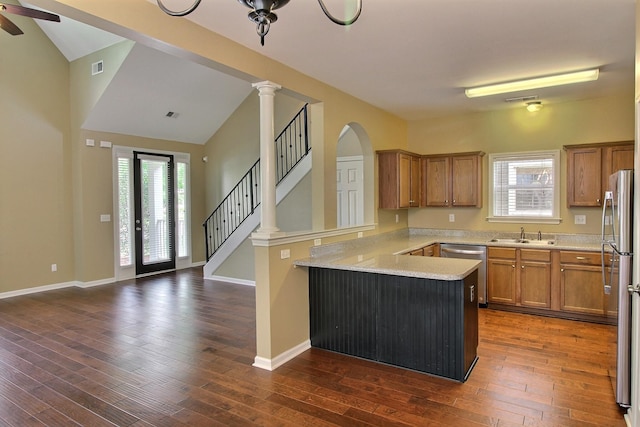 1354 E Island Pl, Memphis, TN 38103 - kitchen with stainless steel appliances, a peninsula, brown cabinetry, healthy amount of natural light, and vaulted ceiling