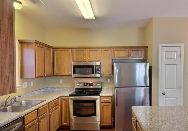 1354 E Island Pl, Memphis, TN 38103 - kitchen featuring appliances with stainless steel finishes, a sink, light countertops, and brown cabinetry