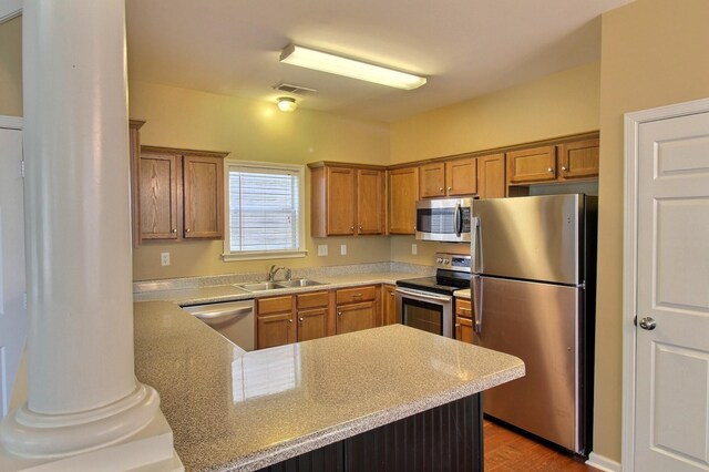 1354 E Island Pl, Memphis, TN 38103 - kitchen featuring stainless steel appliances, a sink, a peninsula, brown cabinetry, and wood finished floors