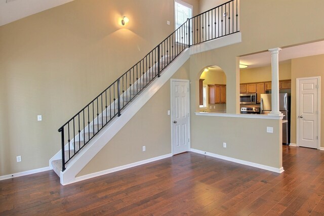 1354 E Island Pl, Memphis, TN 38103 - stairway featuring a high ceiling, ornate columns, wood finished floors, baseboards, and arched walkways