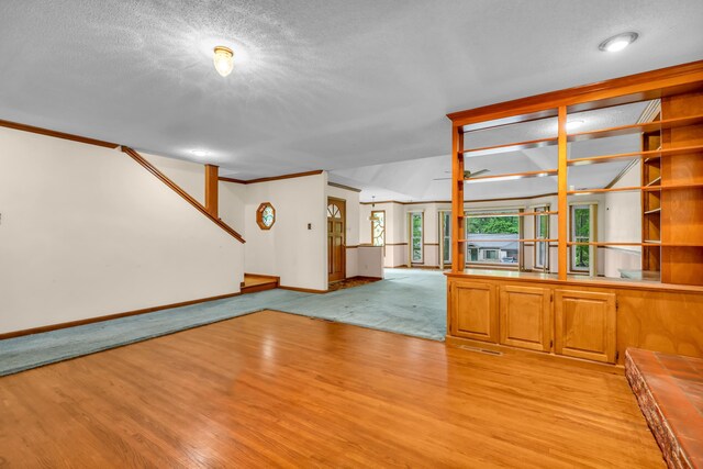 6196 Ivanhoe Cv, Bartlett, TN 38134 - empty room with baseboards, light wood-style floors, a textured ceiling, crown molding, and stairs