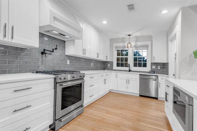 185 Alexander St, Memphis, TN 38111 - kitchen with appliances with stainless steel finishes, premium range hood, light countertops, white cabinetry, and backsplash