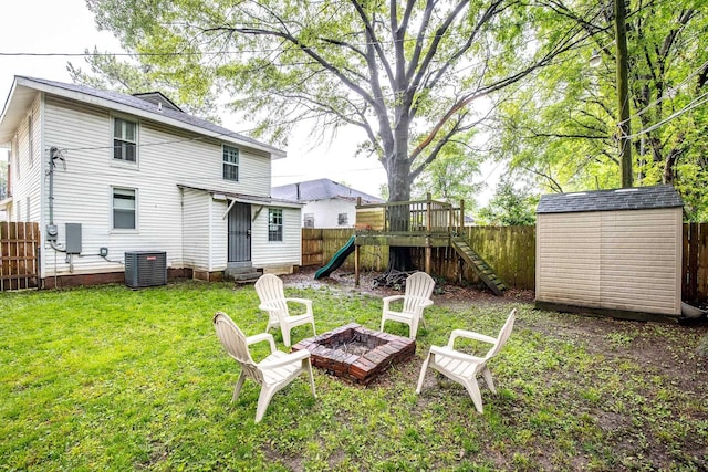 view of yard featuring central AC, a fire pit, a shed, an outbuilding, and entry steps