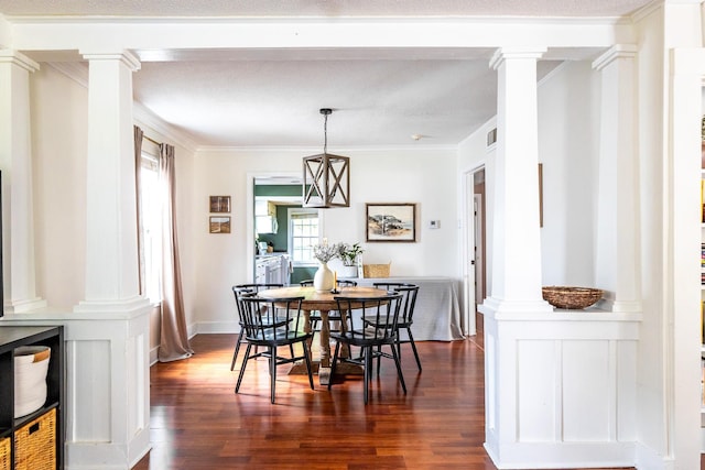dining space with ornate columns, dark wood finished floors, and ornamental molding