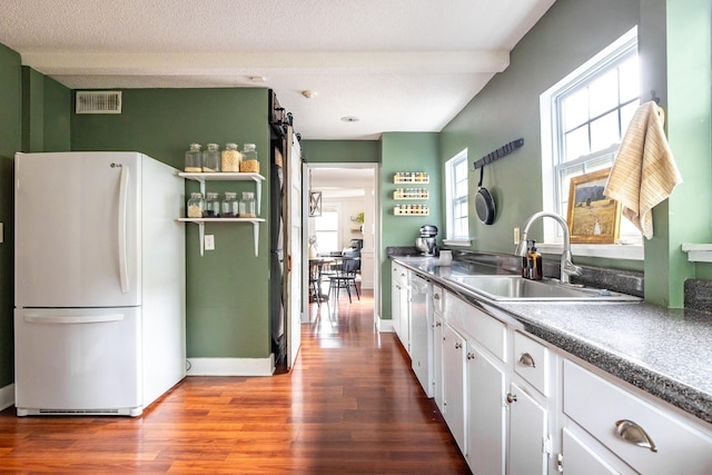 kitchen featuring freestanding refrigerator, a sink, wood finished floors, white cabinets, and dishwasher