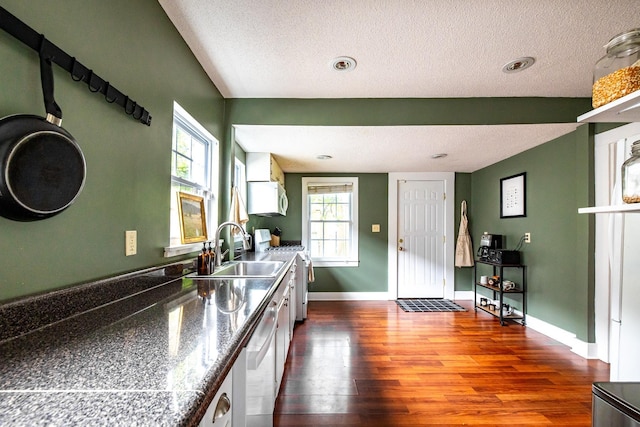 kitchen featuring gas stove, a sink, white microwave, dark wood-type flooring, and dark countertops